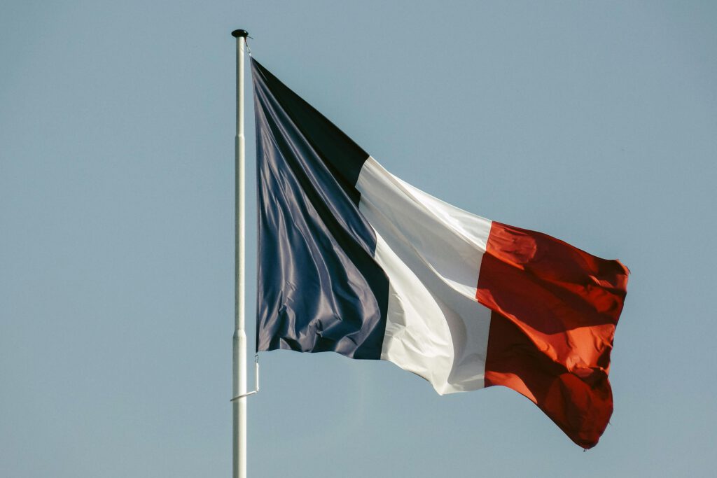 A French flag waving against a clear blue sky, symbolizing national pride and patriotism.