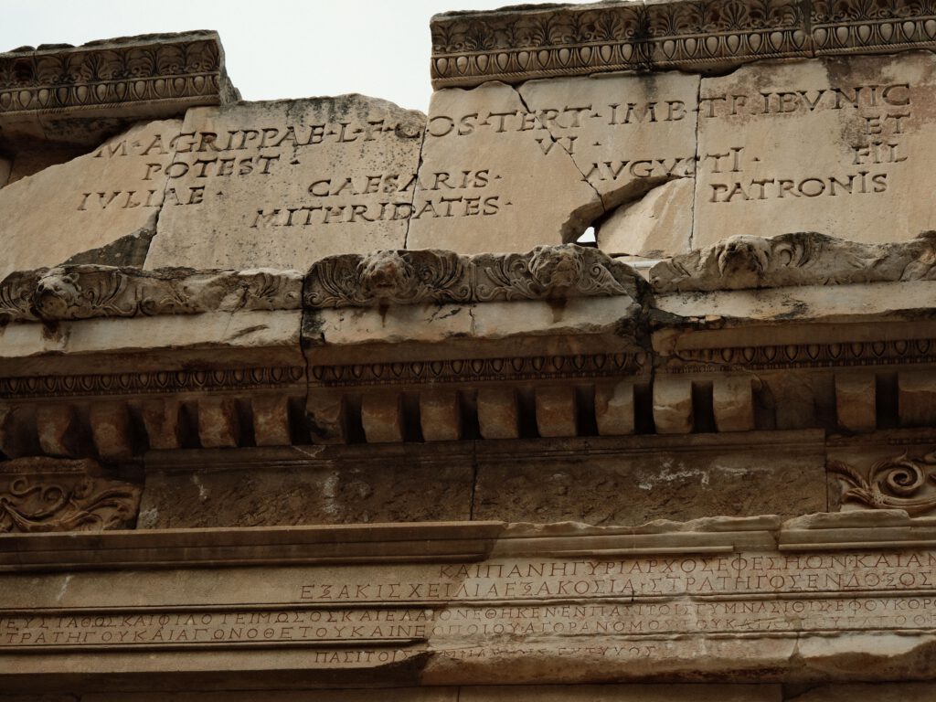 Close-up of ancient Roman architecture featuring Latin inscriptions carved into stone.